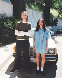 a man and a woman standing in front of a car wearing clothes made from hemp fabric
