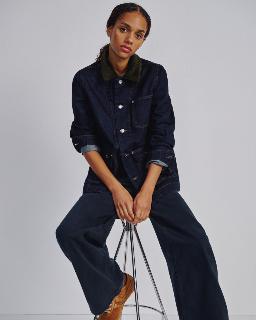 A woman sitting on a chair wearing a full denim outfit made by affordable sustainable fashion brand Everlane