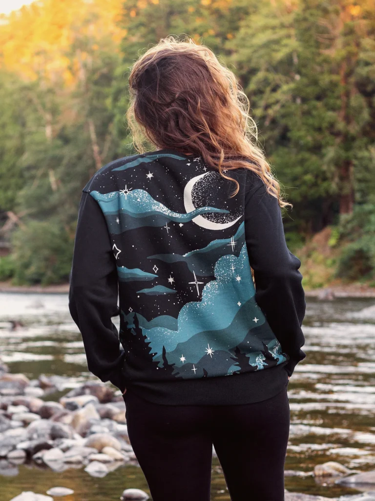 woman wearing an organic sweatshirt with a celestial print from affordable sustainable clothing brand Happy Earth