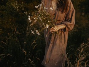 woman wearing a sustainable dress holding flowers in a field
